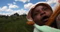 Une mère en liberté relative, alors que l'économie du pays est en lambeaux, transporte son enfant sur son dos au Zimbabwe.（Staff: ALEXANDER JOE / 2009 AFP）  