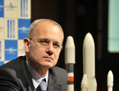 u00abJean Yves Le Gall, président d’Arianespace, assis devant les trois lanceurs: Ariane, Soyouz et Véga».（Staff: YOSHIKAZU TSUNO / 2011 AFP）  
