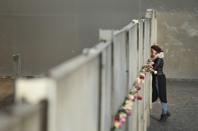 Une femme dépose des fleurs sur les vestiges du mur de Berlin lors du 26e anniversaire de sa démolition, le 9 novembre 2015. De 1961 à 1989, ce mur, construit pour empêcher les Allemands de l'est d'émigrer vers l'Occident démocratique, était un symbole de la guerre froide et du communisme soviétique. (Sean Gallup/Getty Images)