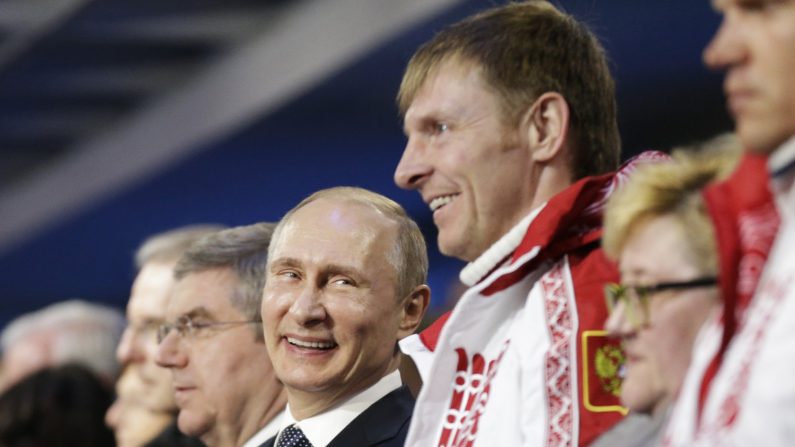 Le président russe Vladimir Poutine (C) aux côtés d'Alexander Zubkov, médaillé d'or russe des épreuves d’équipes de bobsleigh à deux puis à quatre, lors de la cérémonie de clôture des Jeux olympiques d'hiver de Sotchi le 23 février 2014. (David Goldman/AFP/Getty Images)