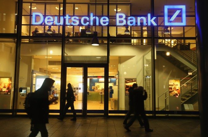 Des passants devant une antenne de la Deutsche Bank, le 9 février 2016 à Berlin. Trois fonds spéculatifs ont arrêté les échanges de produits dérivés avec la banque, la mettant dans une situation délicate. (Sean Gallup/Getty Images)