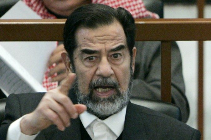 L’ancien Président Irakien Saddam Hussein lève le doigt tout en écoutant les accusations lors de son procès pour le génocide ‘Anfal’, le 4 décembre 2006 à Bagdad, Irak. Saddam Hussein et six co-accusés sont jugés sur des accusations d’assassinats de kurdes lors de la campagne ‘Anfal’ de 1987-88. L'ancien chef d'État irakien aurait maintenu une chambre de torture à la Mission de l’Irak située à New York City. (Nikola Solic-Pool/Getty Images)


