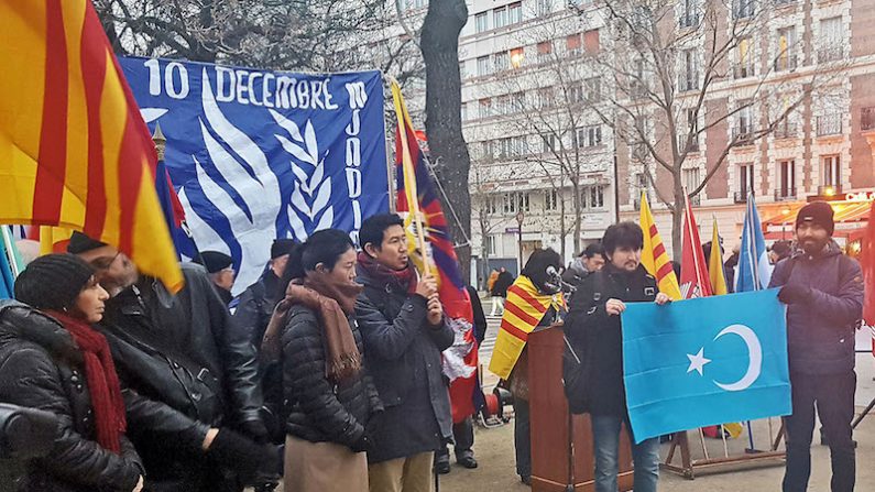 Deux militants déploient un drapeau du Turkestan, le samedi 10 décembre, à Paris. (Epoch Times)