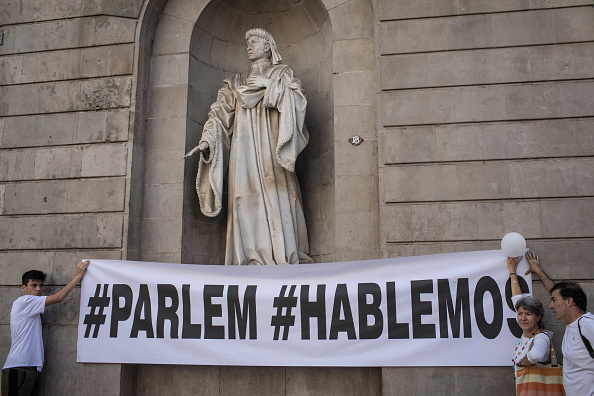 Devant la mairie de Barcelone, une banderole disant "dialoguons" "alors que des centaines de personnes vêtues de blanc se sont rassemblées devant les mairies et les églises à Barcelone et à Madrid avec le même slogan "dialoguons" exprimé dans les deux langues :  "parlem" et "hablemos".
(Chris McGrath/Getty Images)