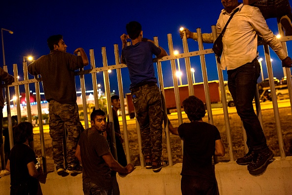 Des migrants tentent de sauter par-dessus une clôture dans un terminal de ferry à Patras, au sud-ouest de la Grèce.(ANGELOS TZORTZINIS / AFP / Getty Images)