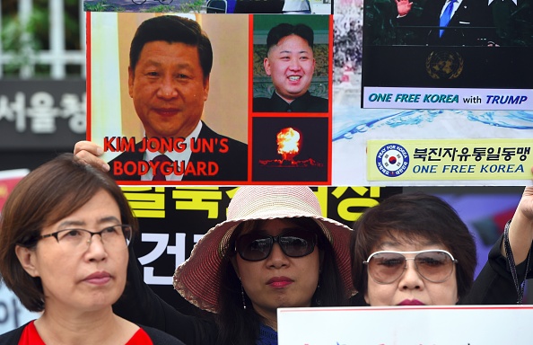 Les anciens transfuges nord-coréens brandissent une affiche montrant le président chinois Xi Jinping (G) et le dirigeant nord-coréen Kim Jong-Un (C) lors d'un rassemblement anti-nord-coréen devant le complexe gouvernemental sud-coréen à Séoul le 22 septembre 2017.
(JUNG YEON-JE/AFP/Getty Images)