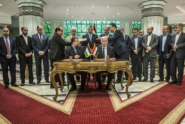 Le nouveau leader adjoint du Hamas Salah al-Aruri (assis G) et Azzam al-Ahmad du Fatah (assis D) lors de la signature de l'accord de réconciliation du Caire le 12 octobre 2017. Selon l'accord, l'Autorité palestinienne basée en Cisjordanie doit reprendre le contrôle total de la bande de Gaza contrôlée par le Hamas d'ici au 1er décembre, selon un communiqué du gouvernement égyptien. /
(KHALED DESOUKI / AFP / Getty Images)