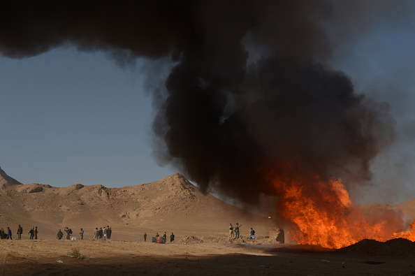 Un policier se tient près d'une pile de stupéfiants en flammes.
 (HOSHANG HASHIMI / AFP / Getty Images)