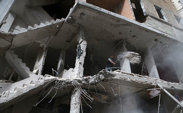 Un Syrien enlève des débris de l'étage supérieur d'un immeuble après les bombardements des forces du régime dans la ville rebelle de Kafr Batna, dans la banlieue de Damas, le 20 novembre 2017. 
(ABDULMONAM EASSA / AFP / Getty Images)