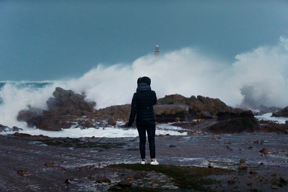 Une femme regarde des vagues s'écraser contre le front de mer à Auderville, en Normandie, alors que la tempête Eleanor frappe le nord de la France le 3 janvier 2018. 
(CHARLY TRIBALLEAU/AFP/Getty Images)