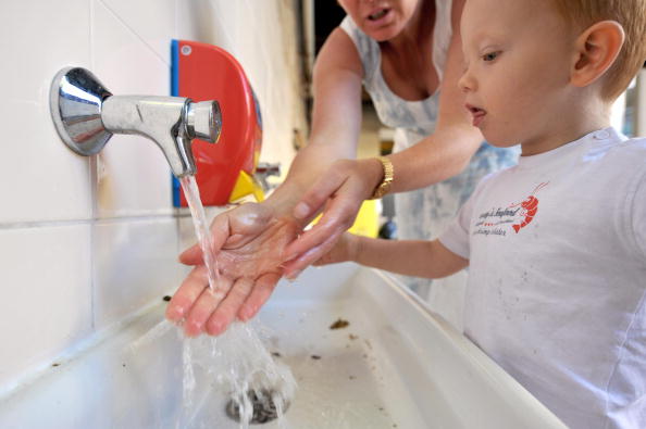 Une femme montre à un enfant comment se laver les mains à l'Institut Sainte Marie, à Caen, dans le nord-ouest de la France. La grippe se transmet au moment où des millions d'écoliers se préparent à retourner à l'école. Le ministère de la santé craignant que le virus ne se propage facilement entre les salles de classe, lance une grande campagne de prévention. (MYCHELE DANIAU / AFP / Getty Images)