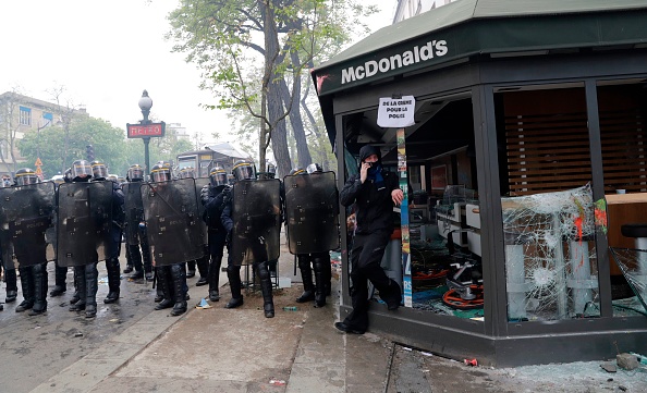 Des agents de la police anti-émeute du CRS se tiennent à côté d'un restaurant McDonalds endommagé lors de la manifestation du 1er mai 2018 à Paris. Thomas SAMSON AFP / Getty Images)