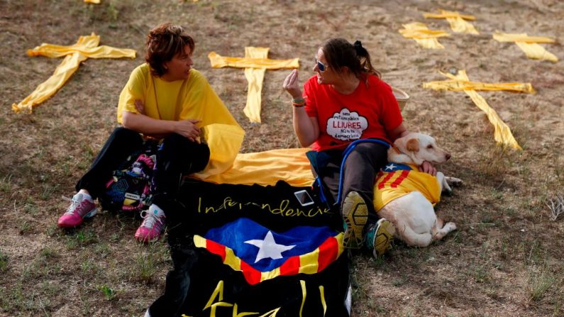 Des femmes assises à côté de rubans jaunes en forme de croix sur la plage lors d'une manifestation de soutien aux dirigeants séparatistes emprisonnés. Photo devrait lire PAU BARRENA / AFP / Getty Images
