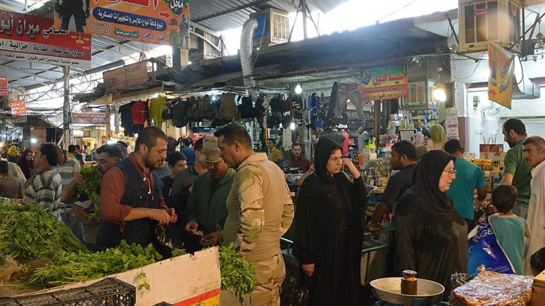 Des hommes et des femmes irakiennes achètent de la nourriture dans un marché en plein air après avoir rompu le jeûne pendant le mois sacré du Ramadan à Mossoul le 24 mai 2018. Le groupe État islamique (EI) qui contrôlait la ville pendant trois ans avant son éviction en juillet avait banni les traditions qui composent l'esprit festif du mois du jeûne de l'aube au crépuscule. Photo ZAID AL-OBEIDI / AFP / Getty Images.
