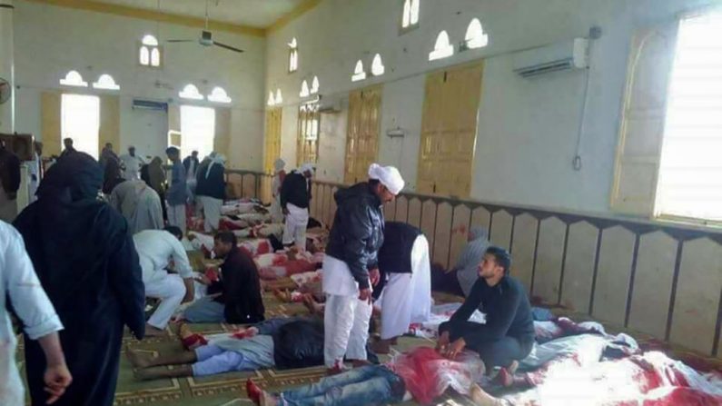 Des Égyptiens passent devant des cadavres à la suite d'une attaque à la mosquée de Rawda, à environ 40 kilomètres à l'ouest de El-Arish, capitale du nord du Sinaï. Des explosifs ont ravagé la mosquée pour les prières hebdomadaires du vendredi. Photo STRINGER / AFP / Getty Images.