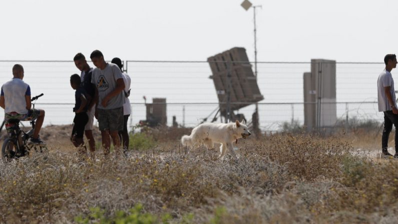 Le 14 juillet 2018. Les Israéliens se tiennent à côté d'un système de défense, conçu pour intercepter et détruire les roquettes à courte portée et les obus d'artillerie, près de la ville d'Ashkelon. Photo AHMAD GHARABLI / AFP / Getty Images.