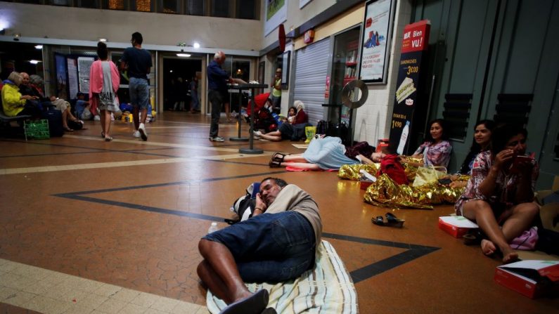 Un homme se repose alors que lui et les autres attendent à la gare de Lisieux, dans le nord-ouest de la France, après l’annulation des trains suite à un orage le 7 août 2018. Photo CHARLY TRIBALLEAU / AFP / Getty Images.