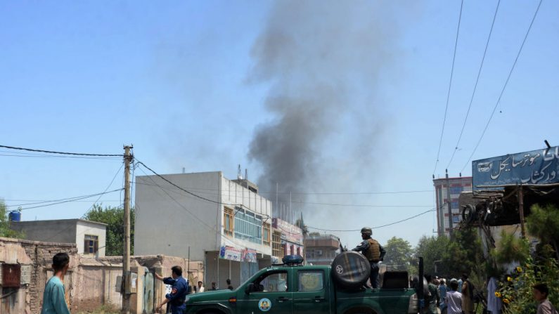Les forces de sécurité afghanes sécurisent une route alors que la fumée s'échappe du site de l'attentat suicide. Photo NOORULLAH SHIRZADA / AFP / Getty Images.