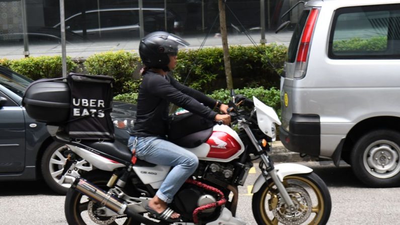 -Un livreur d'Uber sur une route de Singapour le 24 septembre 2018. Singapour, a imposé une amende de 9,5 millions de dollars à Grab et Uber pour avoir enfreint les règles de la concurrence en jetant des barrages routiers pour les concurrents. Photo ROSLAN RAHMAN / AFP / Getty Images.