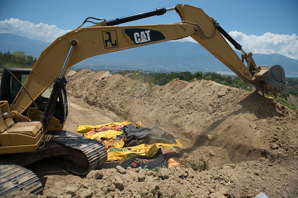 -Une pelle est utilisée pour enterrer les victimes du séisme dans une fosse commune à Palu, 1er Octobre 2018, après le tremblement de terre et le tsunami ont frappé la région le 28 Septembre. Les autorités luttent pour éviter les maladies. Photo BAY ISMOYO / AFP / Getty Images.