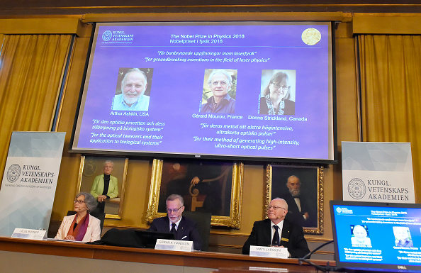 -Un écran présente les portraits d'Arthur Ashkin des États-Unis, de Gérard Mourou de France et de Donna Strickland du Canada lors de l'annonce des lauréats du prix Nobel de physique 2018 à l'Académie royale des sciences de Suède, le 2 octobre 2018 à Stockholm. Photo HANNA FRANZEN / AFP / Getty Images.