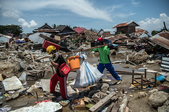 -Les gens transportent des objets de récupération à travers les gravats des bâtiments qui ont été détruits par un tremblement de terre, le 2 octobre 2018 à Palu, en Indonésie. Photo Carl Court / Getty Images.