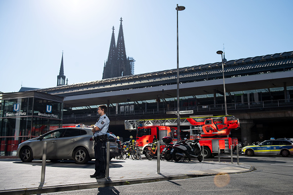 Des policiers et des pompiers le 15 octobre 2018 devant la gare principale de Cologne, dans l'ouest de l'Allemagne, avec la cathédrale de Cologne à l'arrière-plan.  La police allemande a déclaré qu'un homme inconnu, apparemment armé, avait pris une femme en otage une pharmacie à l'intérieur de la gare centrale de Cologne.  (Photo : rMARIUS BECKER/AFP/Getty Images)