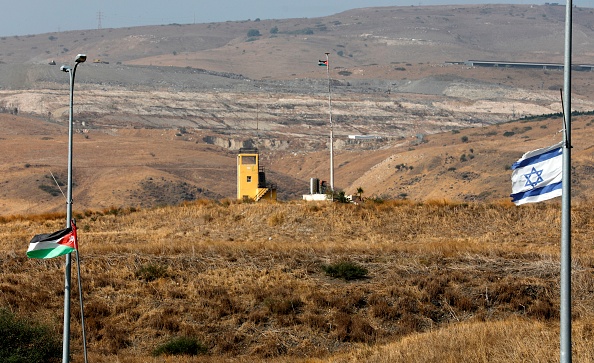 -Une photo prise du côté israélien de la barrière frontalière à Naharayim, également connue sous le nom de Baqura en Jordanie, montre un avant-poste militaire jordanien ainsi que des drapeaux israélien et jordanien dans la vallée du Jourdain, dans le nord d'Israël, le 22 octobre 2018. Photo MENAHEM KAHANA / AFP / Getty Images.