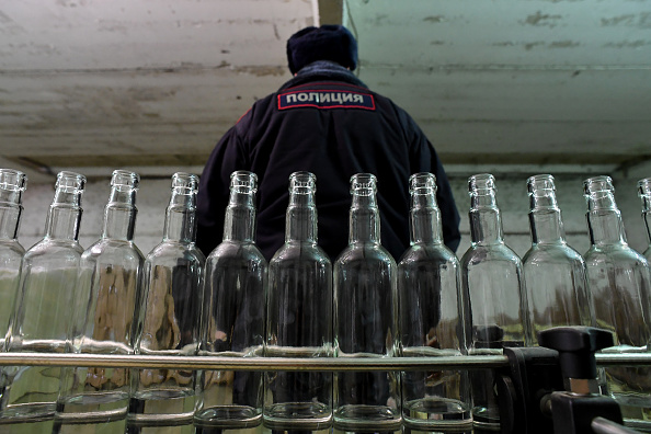 -« Photo d’Illustration » un policier se trouve à l'intérieur d'une distillerie illicite, une grange abandonnée cache une distillerie illicite qui produit des milliers de bouteilles d’alcool pour le marché noir. Photo KIRILL KUDRYAVTSEV / AFP / Getty Images.