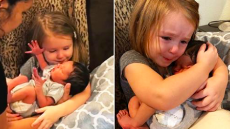 Des larmes montent aux yeux de cette petite fille alors qu’elle câline sa cousine nouveau-née pour la première fois
