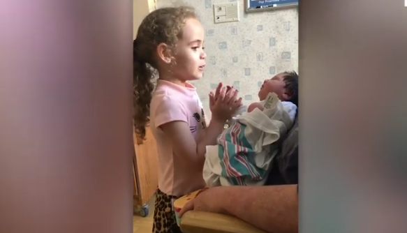 Une fille adorable chante une berceuse lors de sa première rencontre avec sa sœur nouveau-née