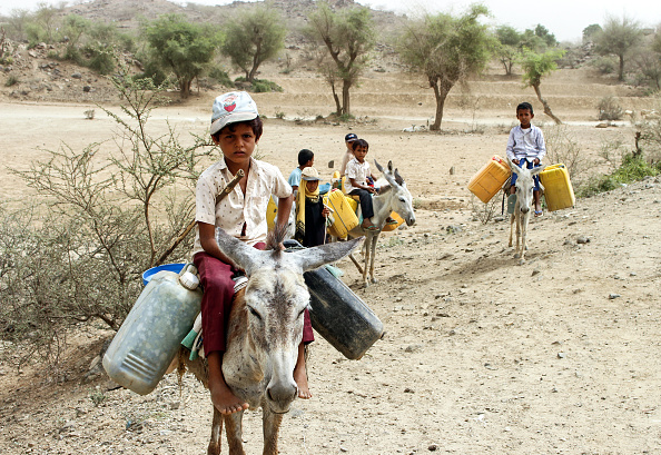 -Des enfants yéménites déplacés chevauchent des ânes chargés de jerricans pour aller chercher de l'eau dans un camp de fortune situé dans le district de Hajjah, dans le nord du pays, juillet 2018. Photo : ESSA AHMED / AFP / Getty Images.