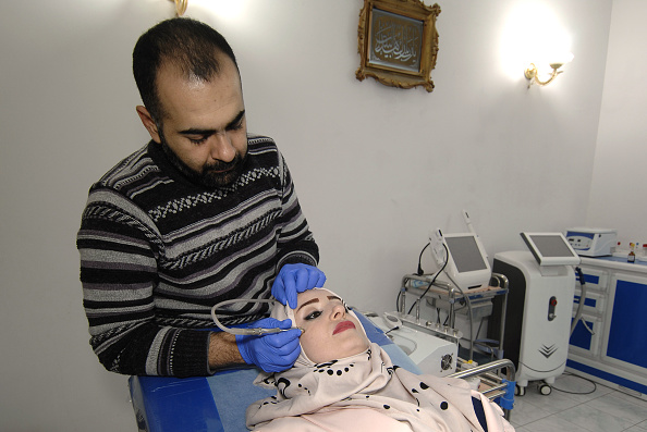 -Une femme irakienne se fait soigner le visage dans une clinique de beauté à Mossoul le 19 novembre 2018. Pendant trois ans, les femmes de Mossoul étaient couvertes de noir de la tête aux pieds et les hommes devaient garder la barbe longue. Les salons ont été fermés et la chirurgie plastique considérée comme un crime. Photo ZAID AL-OBEIDI / AFP / Getty Images.