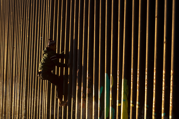 -Le 8 décembre 2018, Jonatan Matamoros Flores, un migrant hondurien voyageant avec la caravane de migrants d'Amérique centrale, escalade la barrière frontalière américano-mexicaine à Tijuana, dans l'État de Basse-Californie, au Mexique. GUILLERMO ARIAS / AFP / Getty Images.