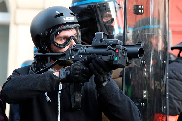 Un policier montre du doigt un lance-balles défensif en caoutchouc de 40 millimètres LBD (LBD 40) avec une caméra attachée lors d'une manifestation à Paris le 9 février 2019, alors que les manifestants des " Gilets Jaunes " descendent dans la rue pour le 13e samedi consécutif.    (Photo : ZAKARIA ABDELKAFI/AFP/Getty Images)
