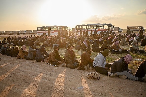 -Des hommes soupçonnés d'être des combattants de l'État islamique attendent d'être repérés par les membres des Forces démocratiques syriennes (SDF) dirigées par les Kurdes, après avoir quitté le dernier groupe de Baghouz. Le 22 février 2019. Photo de Bulent KILIC / AFP / Getty Images.