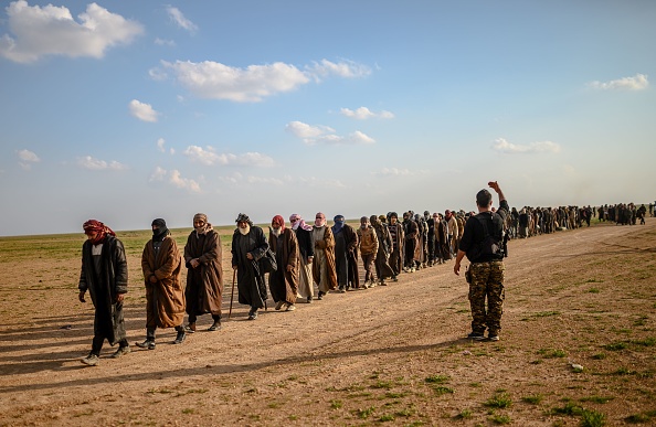 -Des hommes soupçonnés d'être des combattants de l'Etat islamique (EI) attendent d'être repérés par des membres des Forces démocratiques syriennes dirigées par les Kurdes après avoir quitté le camp du groupe de l'Etat islamique à Baghouz, 2019. Photo de Bulent KILIC / AFP / Getty Images.