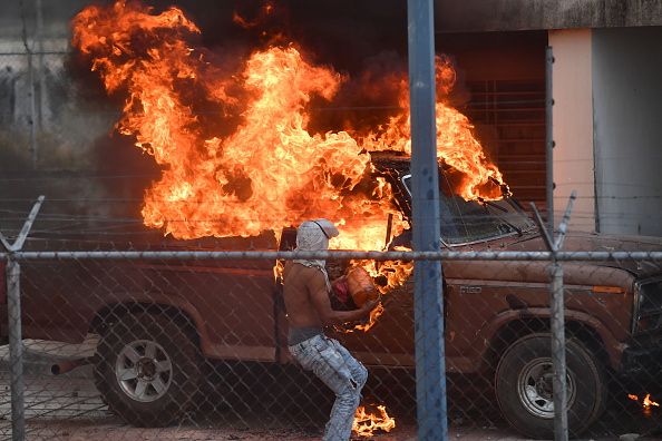 -Un véhicule est incendié dans un commissariat de police vénézuélien à la frontière avec Pacaraima, dans l'État de Roraima, au Brésil, où des affrontements avec les forces de sécurité ont éclaté alors que des efforts étaient déployés pour acheminer de l'aide dans le pays frappé par la crise, le 23 février 2019. Photo NELSON ALMEIDA / AFP / Getty Images.