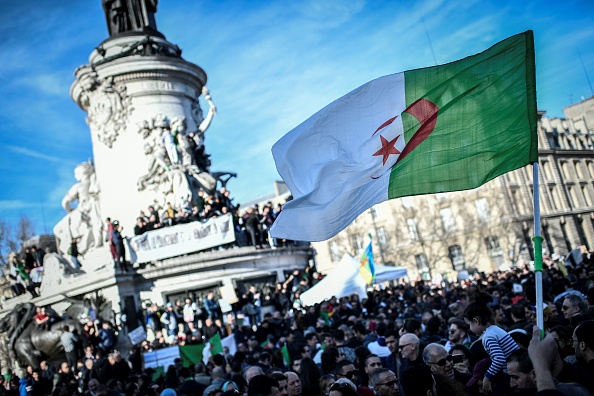 -Un manifestant brandit le drapeau algérien lors d'un rassemblement contre la candidature du président algérien à un cinquième mandat le 24 février 2019 sur la place de la République à Paris. Photo de STEPHANE DE SAKUTIN / AFP / Getty Images.