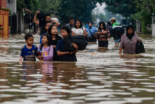 -Des résidents marchent le long d'une route inondée lors de l'évacuation du village de Dayeuhkolot à Bandung, dans la province de Java occidental. Environ 6 000 maisons ont été inondées par le fleuve Citarum qui déborde, en raison des fortes pluies dans la région. Photo par TIMUR MATAHARI / AFP / Getty Images.