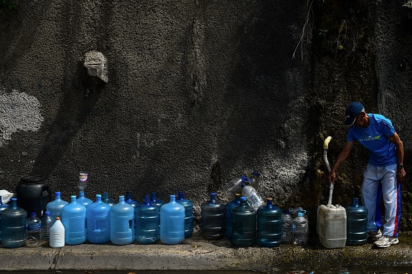 -Un homme remplit des conteneurs avec de l'eau qui coule de la montagne de Wuaraira Repano, également appelée "El Avila", à Caracas le 13 mars 2019. Photo de FEDERICO PARRA / AFP / Getty Images.