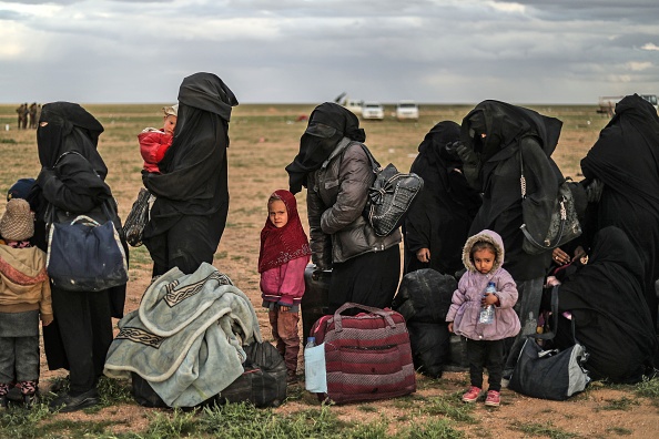 Le 27 février 2019, des femmes et des enfants de djihadistes font la queue pour être fouillés après s’être rendus aux troupes des Forces démocratiques syriennes (FDS) près de la ville de Baghouz, au nord-est de la Syrie. Crédit : DELIL SOULEIMAN/AFP/Getty Images.