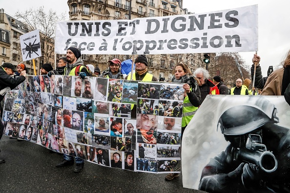 Des manifestants brandissent une banderole représentant des blessés, à côté d'un dessin d'un policier pointant un lance-balles défensif en caoutchouc de 40 millimètres LBD, lors d'une marche le 2 février 2019 à Paris.   (Photo : FRANCOIS GUILLOT/AFP/Getty Images)