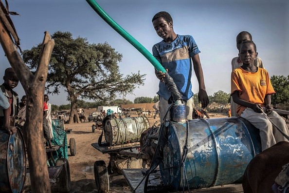 -De jeunes colporteurs remplissent des barils avec de l'eau dans les oueds Moura à Hadjer Hadid, dans la région du Ouaddaï, dans l'est du Tchad, le 24 mars 2019. Photo de Amaury HAUCHARD / AFP / Getty Images.