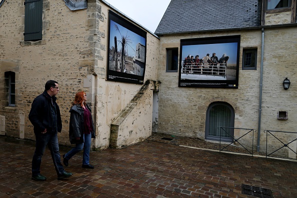 -Les gens défilent devant des photographies d'Ayman Oghanna exposées dans une rue de Bayeux, dans le nord-ouest de la France, lors de la 22e édition du prix Bayeux-Calvados pour les correspondants de guerre. Cette année l'événement aura lieu du 7 au 13 octobre 2019 et sera présidé par Gary Knight. Photo CHARLY TRIBALLEAU / AFP / Getty Images.