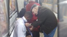 Un homme âgé montre à un jeune homme comment nouer une cravate à la gare ferroviaire après l’avoir vu se démener en vain pour le faire
