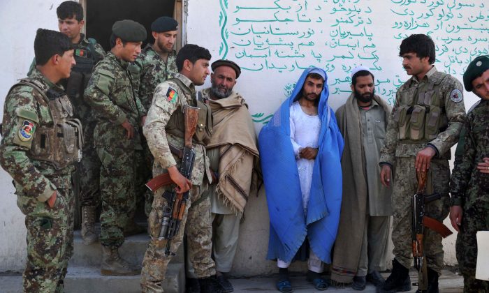 Le 18 mars 2014, des membres du personnel de sécurité afghan présentent au quartier général de l'Armée nationale afghane dans le district de Khogyani, près de Jalalalabad, un résident en burqa, qu'ils disent être un combattant taliban. (Noorullah Shirzada/AFP/Getty Images)
