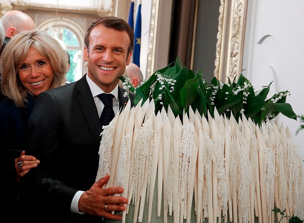 Le président français Emmanuel Macron et son épouse Brigitte posent à côté d'un bouquet de fleurs de muguet lors de la cérémonie annuelle de la fête du Travail, le 1er mai 2019 à l'Élysée à Paris. (Photo : CHRISTOPHE ENA/AFP/Getty Images)