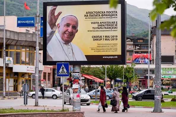 -Les gens marchent sous un panneau d'affichage mettant en vedette le pape François dans la ville de Tetovo le 4 mai 2019, trois jours avant sa visite en Macédoine du Nord, lieu de naissance de la plus célèbre religieuse catholique, Teresa. Photo de Armend NIMANI / AFP / Getty Images.