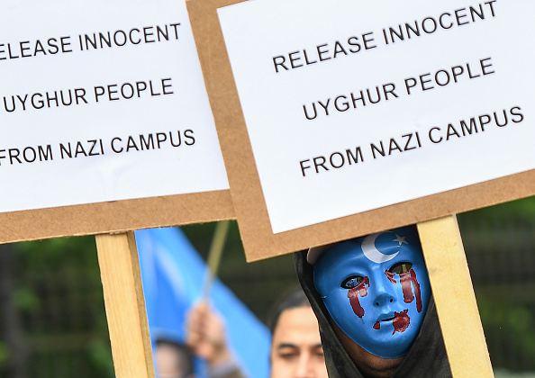 -Une personne portant un masque bleu avec des larmes de sang participe à une marche de protestation de l'ethnie ouïghoure demandant à l'Union européenne d'appeler la Chine à respecter les droits de l'homme dans la région chinoise du Xinjiang et à demander la fermeture d'un "centre de rééducation". Photo de Emmanuel DUNAND / AFP / Getty Images.